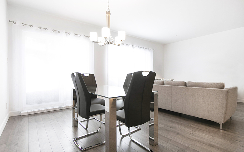 Location d’un logement meublé Pièce à aire ouverte dans un logement meublé avec une salle à manger pourvue d’une table et de chaises, ainsi qu’un salon.