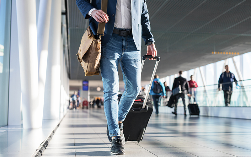 La location temporaire Homme marchant dans un aéroport avec ses bagages.