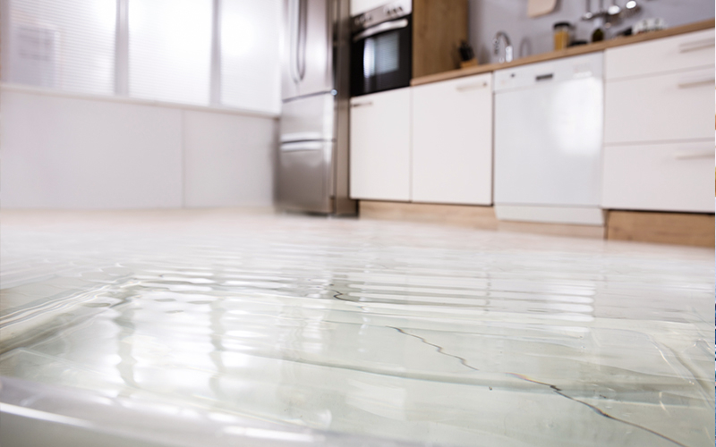 Sinistre : dommage par l’eau Un plancher blanc d’une cuisine recouvert d’eau en raison d’un sinistre.